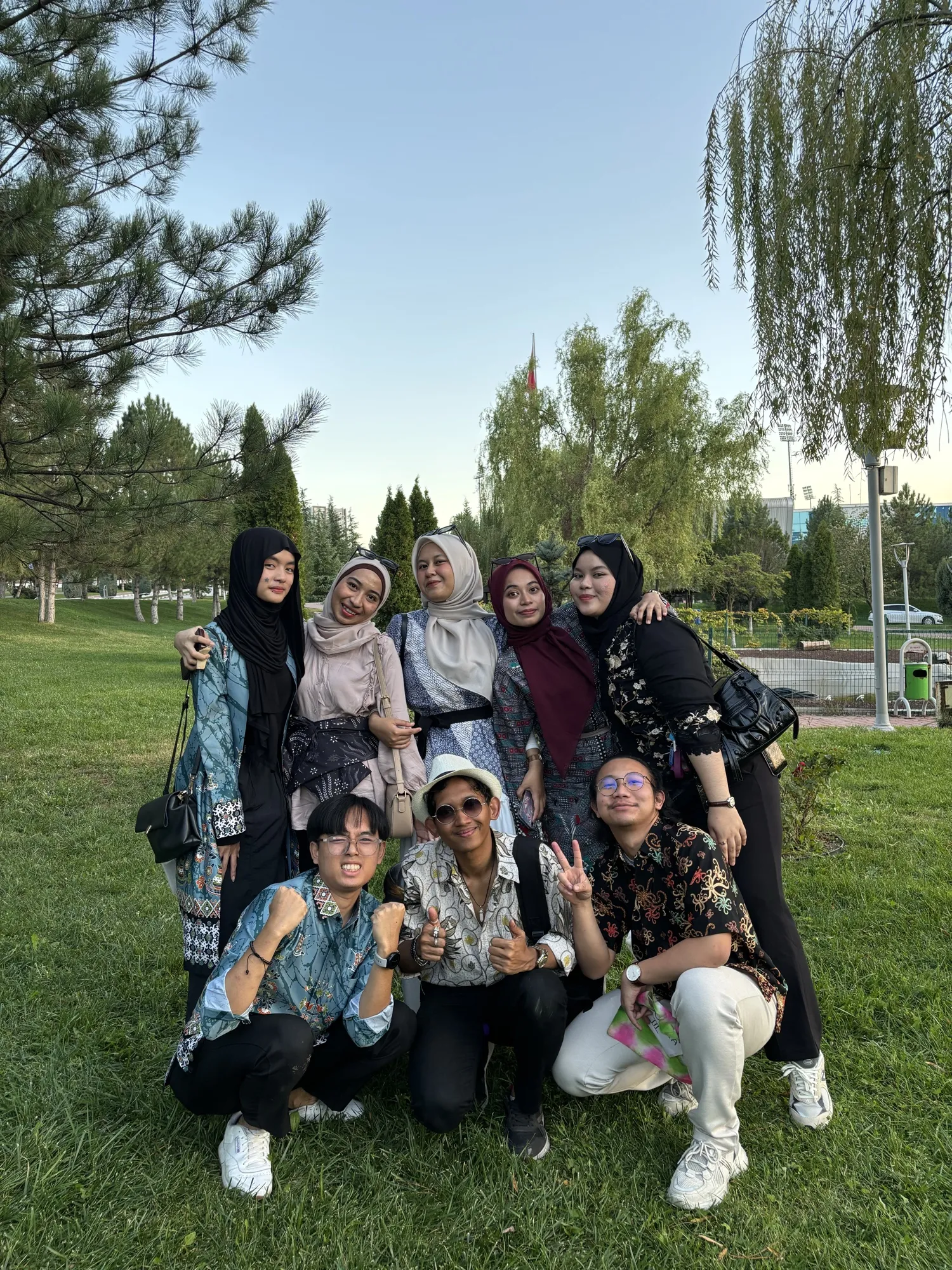 A group of friends posing together on the grass in a park