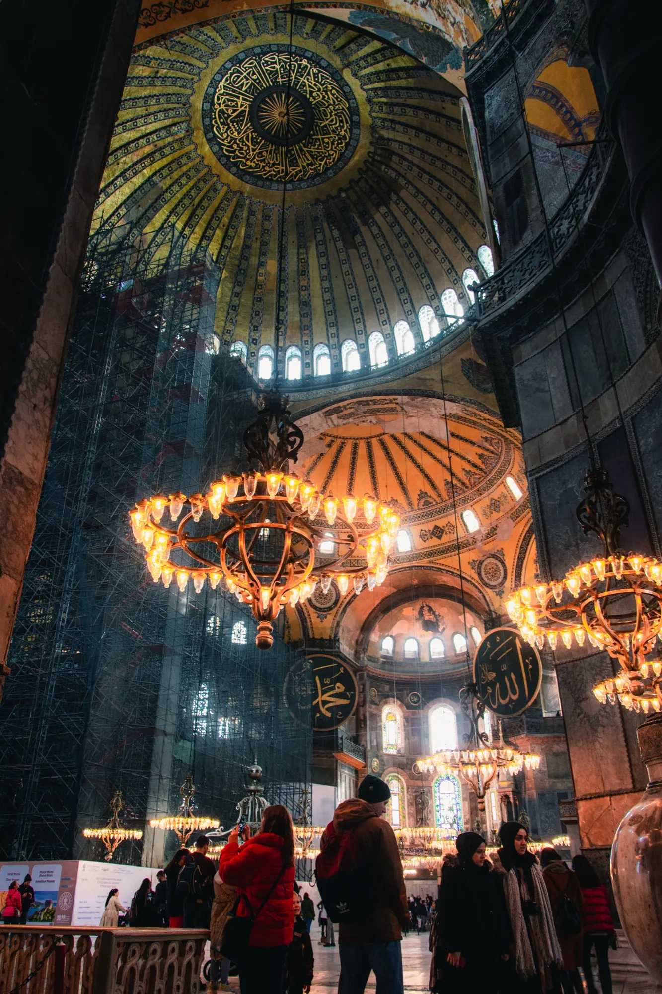 Chandeliers glowing under the domes of Hagia Sophia, with visitors below