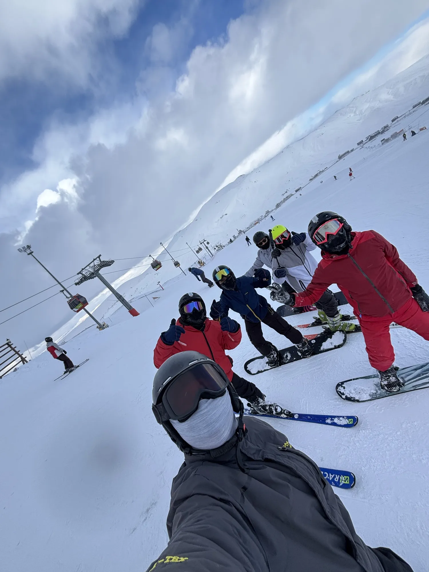 A selfie on a ski slope with friends in snowboard gear behind